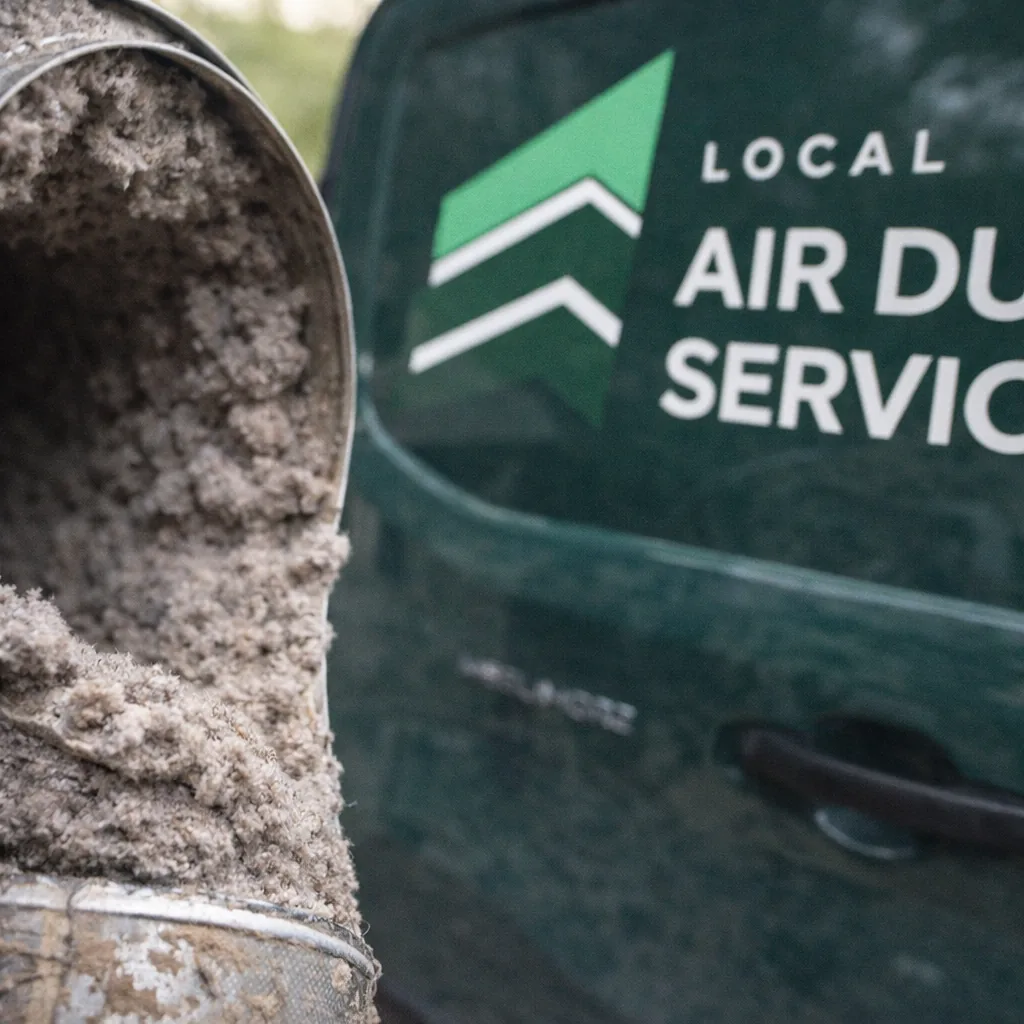 Close-up of a heavily packed dryer vent bend before cleaning, showing why turns take longer to clear